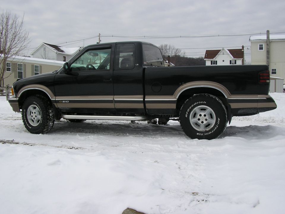 Black pickup truck with tan trim, side view, in snow