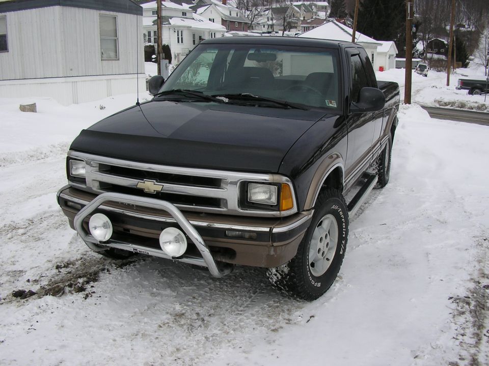 Black Chevrolet S-10 pickup truck with chrome bull bar and fog lights parked in snow