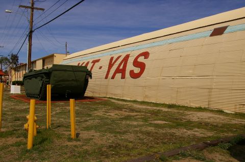 1986 Ford Bronco - Amphibious tracked vehicle on display next to a building with large red lettering.