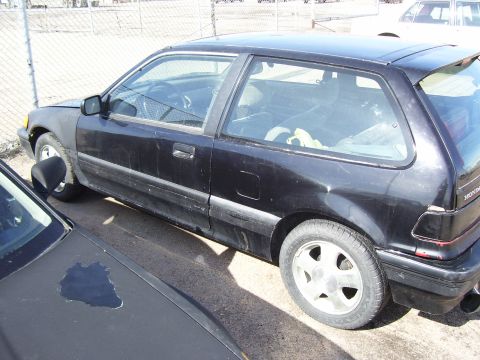 1993 Mazda MX-6 - A black hatchback is parked next to another vehicle, with its front fender mismatched in color.