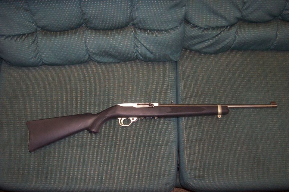 Rifle lying on a green tufted couch