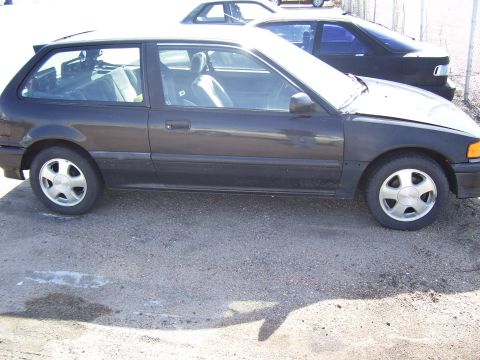 1993 Mazda MX-6 - This dark hatchback is parked next to another vehicle in an outdoor lot.