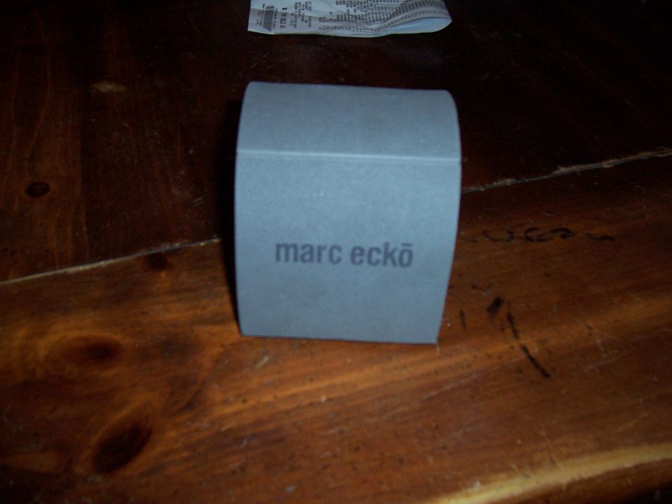 Gray box with 'marc ecko' logo on it, sitting on a wooden table