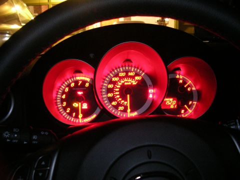 2007 Mazda 3 - The illuminated dashboard gauges of a car, with the speedometer showing approximately 60 mph.