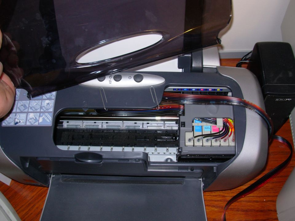 Open inkjet printer showing ink cartridges and ribbon cable internals