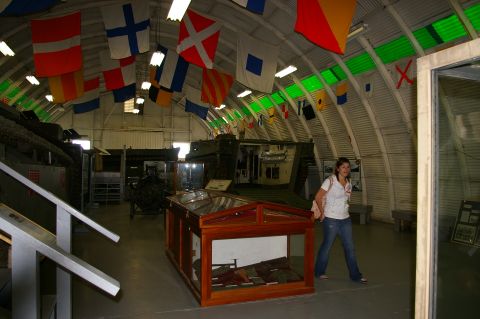 1986 Ford Bronco - A museum displays military vehicles and nautical flags under a curved ceiling.