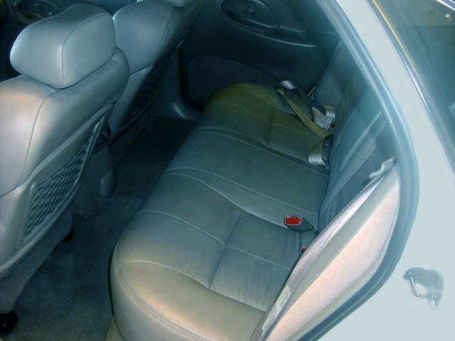 Back seat and door panel of a car. Gray leather seats with seatbelts visible