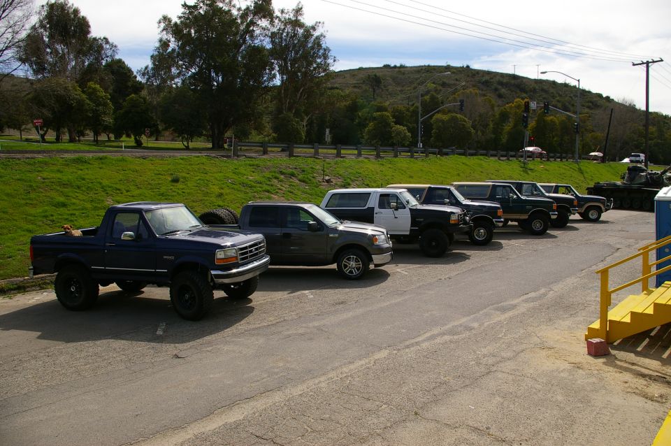Dark blue SUV from the early 1990s parked in a line of trucks