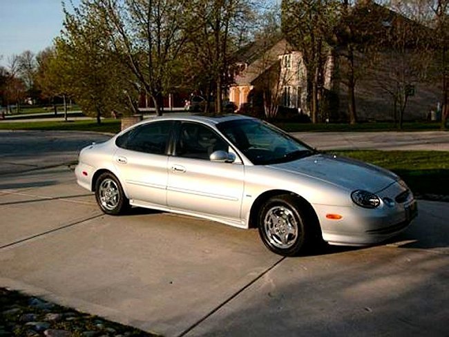 Silver sedan parked on a driveway, house and trees in background