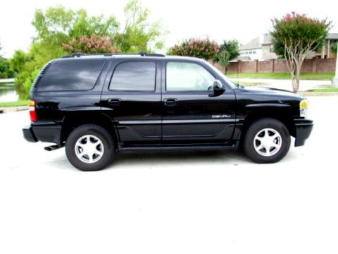 1997 Ford Taurus - Side view of a black GMC Yukon Denali parked near a body of water and trees.