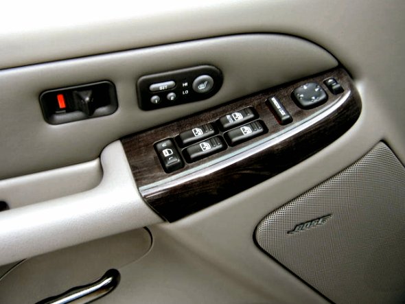 Interior door panel of a 2002 GMC Yukon Denali with wood trim, power window controls, and a Bose speaker