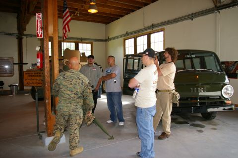 1986 Ford Bronco - A group of people observe a vintage green Dodge van parked indoors.