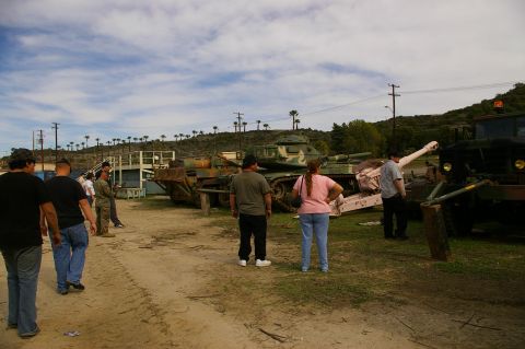 1986 Ford Bronco - People observe various military vehicles, including tanks and a truck, displayed in an outdoor setting.