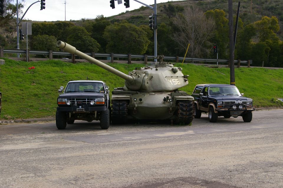 Tank with Y56 marking parked between a dark Ford Bronco and a dark Ford pickup truck