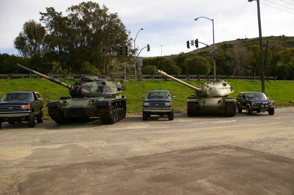 two tanks and three trucks parked on pavement