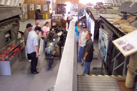 1990 Ford Bronco - Visitors observe military vehicles and displays inside a museum hall.