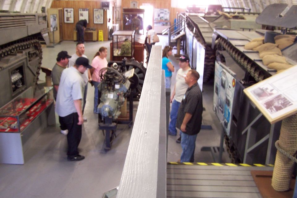 Museum interior with military tanks, display cases, and visitors viewing exhibits