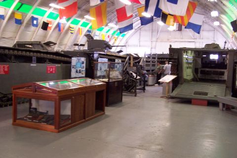 1990 Ford Bronco - A museum displays military vehicles and artifacts under a ceiling adorned with nautical signal flags.