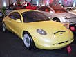 1997 Ford Taurus - A yellow concept car is displayed indoors, with another vehicle visible behind it.