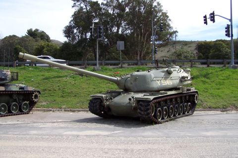 1990 Ford Bronco - A military tank with the designation Y56 is parked on a road next to a grassy embankment and traffic lights.