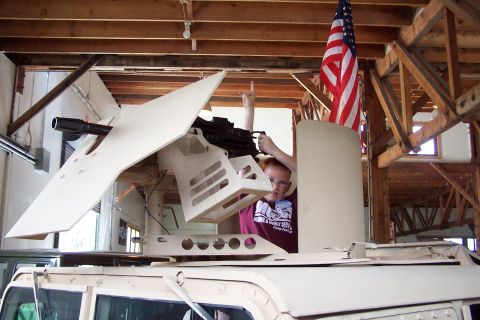 1990 Ford Bronco - A person operates a mounted weapon on a military vehicle inside a building.