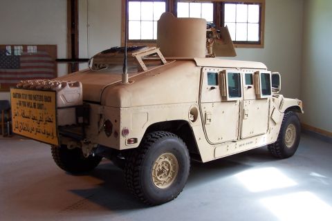 1990 Ford Bronco - A tan military vehicle, possibly a Humvee, is shown from a three-quarter rear view, a mounted turret and a caution sign.