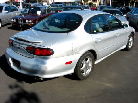 1997 Ford Taurus - This silver sedan is parked in a lot with other vehicles. The rear taillights and spoiler are visible.