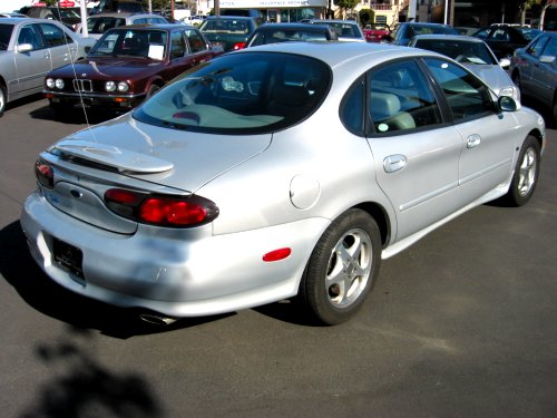 Silver sedan parked in a lot, rear view. Other cars are visible