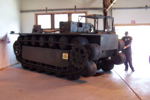1990 Ford Bronco - An amphibious tracked vehicle is displayed indoors with a person attending to it.