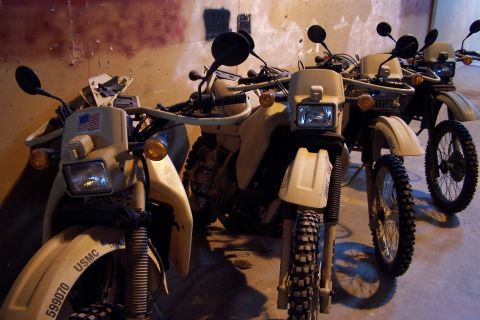 1990 Ford Bronco - Several military-style dual-sport motorcycles are lined up indoors.