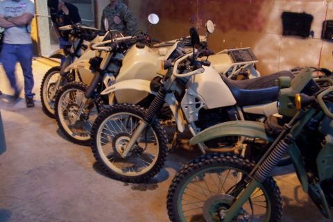 1990 Ford Bronco - Several dual-sport motorcycles are lined up, with some in tan and others in green, suggesting a military or specialized use.