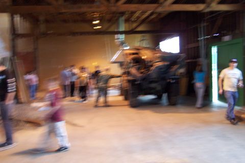 1990 Ford Bronco - A military vehicle is displayed indoors with several people observing it.