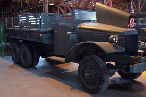 1990 Ford Bronco - This heavy-duty truck features a large wooden cargo bed and a distinctive grille, with its hood raised.