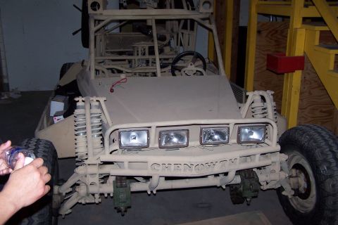 1990 Ford Bronco - A tan Chenoworth dune buggy is parked indoors, showing its front end with multiple headlights and suspension components.