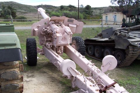 1990 Ford Bronco - An artillery piece is parked outdoors next to other military vehicles.
