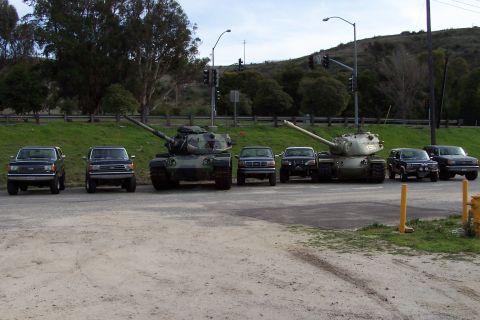 1990 Ford Bronco - Several trucks and tanks are parked in an outdoor lot.