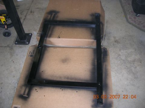 1996 Ford Bronco - Metal frame being spray painted black in a garage setting.