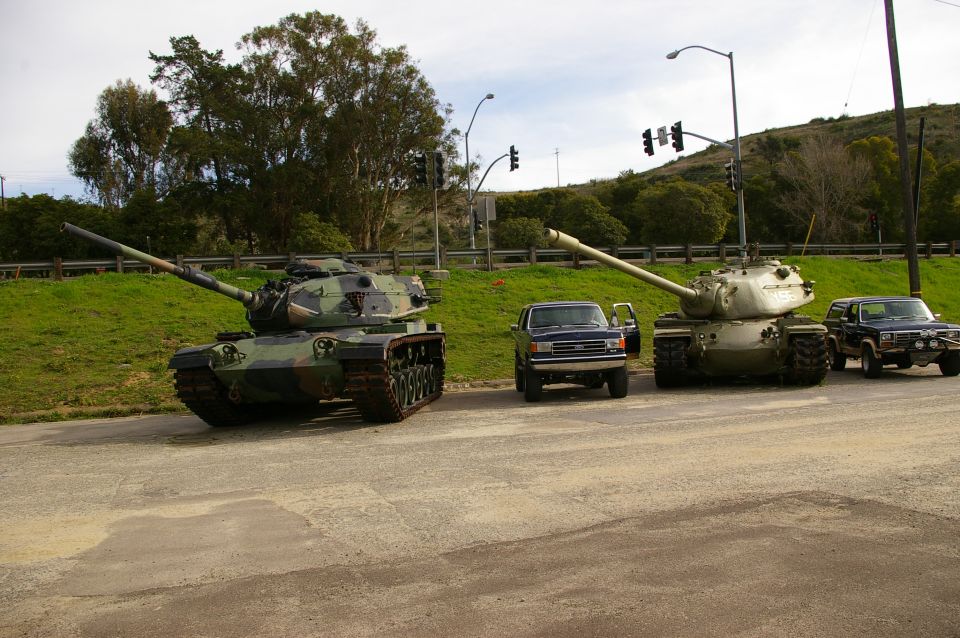 Two tanks and three trucks parked on a road
