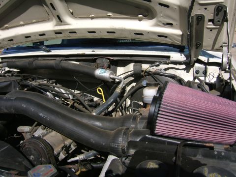 1991 Ford Bronco - Engine bay of a white Ford truck with the hood raised, showing a K&N pink conical air filter clamped to a black intake tube on the passenge…
