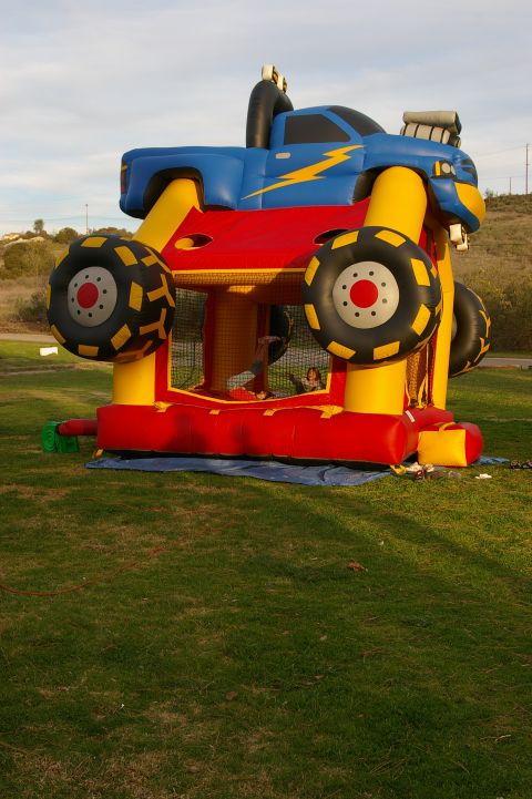 1986 Ford Bronco - An inflatable monster truck bounce house is set up on a lawn with a blue tarp underneath.