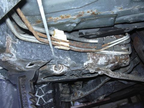 1996 Ford Crown Victoria - Close-up view of the underbody brake lines, showing signs of rust and securing clips.