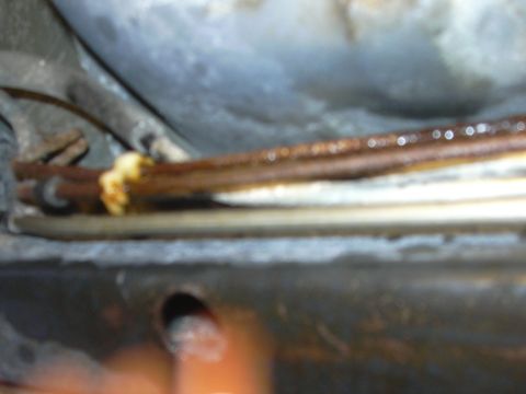1996 Ford Crown Victoria - Close-up view of rusty brake lines, possibly from a vehicle's undercarriage.