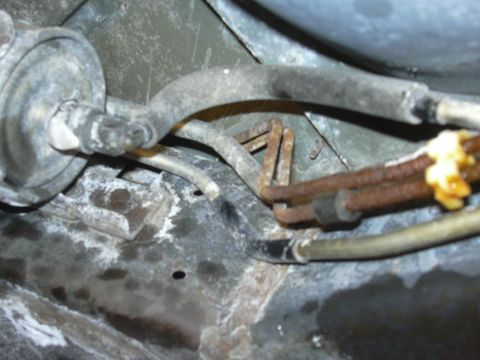 1996 Ford Crown Victoria - Close-up of vehicle fuel lines and filter, showing some rust and yellow sealant.