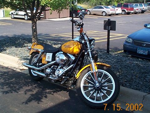 1998 Ford Crown Victoria - A yellow motorcycle is parked in a lot with other vehicles visible in the background.