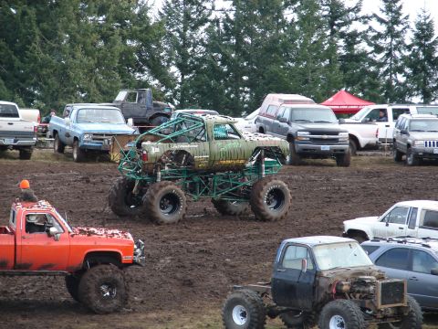 1996 Ford Bronco - Mud bogging event with multiple trucks and vehicles in a muddy field.