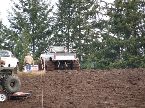 1996 Ford Bronco - A lifted pickup truck navigates a muddy course with large tires, while another vehicle waits.