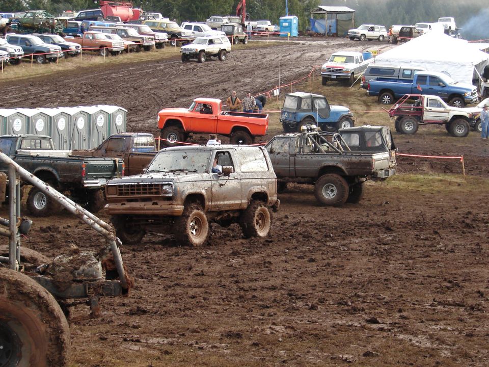 Mud-covered silver Ford Bronco II with aftermarket wheels and tires, angled right