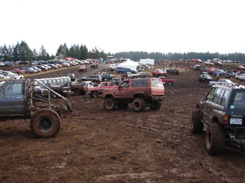 1996 Ford Bronco - A muddy field filled with off-road vehicles during an event.