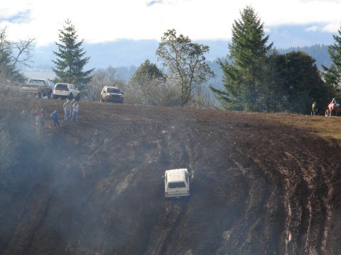 1996 Ford Bronco - Several vehicles and people are gathered on a muddy hill during an outdoor event.