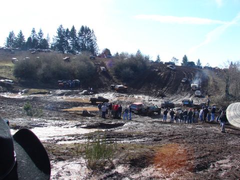 1996 Ford Bronco - A muddy hill is filled with off-road vehicles and spectators participating in an event.